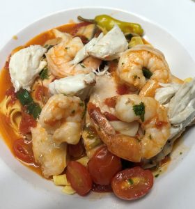 A plate of pasta with shrimp, tomatoes and peppers.