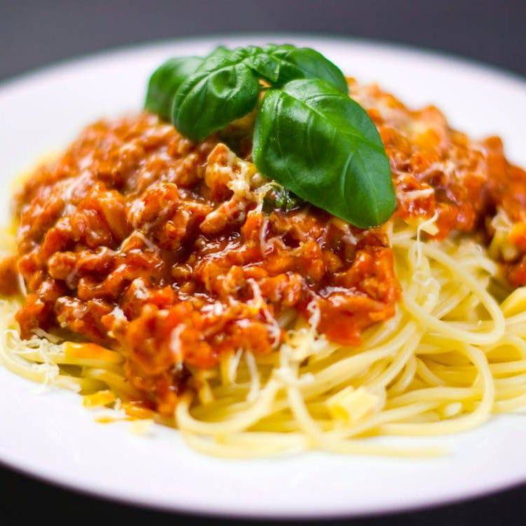A plate of spaghetti with meat sauce and basil.